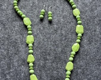 May include: A necklace and matching pair of earrings featuring light green beads in round and faceted geometric shapes. The necklace includes a silver-toned metal clasp shaped like two dragonflies meeting in the center, and the earrings feature silver-toned hooks.