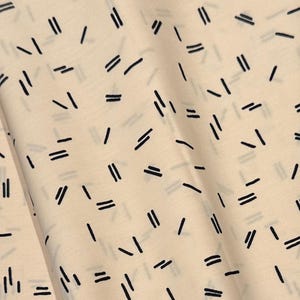 May include: Beige fabric with a repeating pattern of black lines and double lines. The lines are arranged in a random pattern.