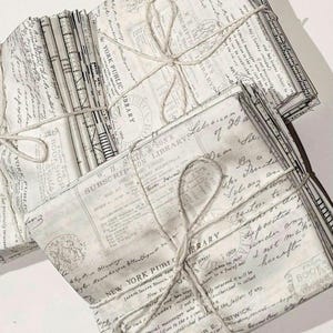 May include: A stack of vintage-style fabric squares with a white background and black text. The fabric is tied together with twine and features text like "New York Public Library" and "Subscription Library".