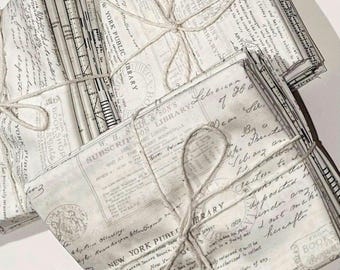 May include: A stack of vintage-style fabric squares with a white background and black text. The fabric is tied together with twine and features text like "New York Public Library" and "Subscription Library".