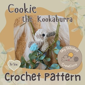 May include: A crochet pattern for a kookaburra bird named "Cookie." The bird is beige, with grey and blue details. The image includes text that reads "Cookie the Kookaburra," "No Sew," and "Crochet Pattern."