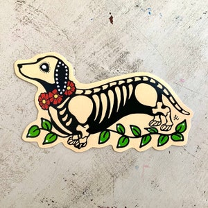 May include: A black and white illustration of a dachshund skeleton with red flowers around its neck. The dachshund is walking on a green vine with leaves.