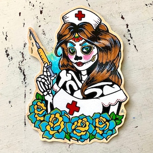 May include: A colorful illustration of a Day of the Dead nurse with a syringe, wearing a white nurse's uniform with a red cross, and surrounded by blue and yellow flowers.