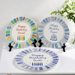 Könnte beinhalten: Drei dekorative Geburtstagsplatten mit personalisiertem Text und farbenfrohen Designs. Jede Platte zeigt einen einzigartigen Namen und eine "Happy Birthday"-Nachricht. Die Platten haben ein genähtes Bordendesign und Kerzenillustrationen.