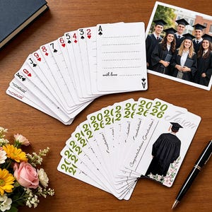May include: A deck of playing cards with a graduation theme. Some cards display traditional suits and numbers, while others feature the year "2026" and the word "Graduation!" A photo of graduates and a pen are also present.