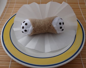 May include: A white and brown stuffed pastry with black chocolate chips on a white paper doily on a yellow and blue plate.