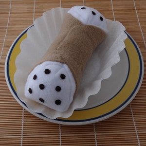 May include: A white and brown stuffed pastry with black chocolate chips on a white and yellow plate.