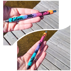 May include: A colorful pen with a rainbow glitter finish and black turtle silhouettes. The pen has the name "Eden" written on it.