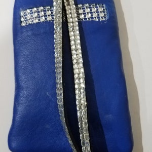 May include: A small blue leather pouch with a silver rhinestone strap. The pouch has a zipper closure and a small loop for attaching a key ring.