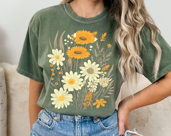 May include: A green t-shirt with a vintage floral print featuring yellow and white daisies. The print is centered on the shirt and covers most of the front.