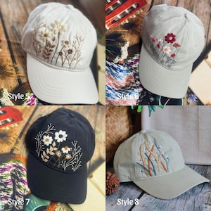 May include: Four baseball caps with embroidered floral designs. Styles include a white cap with beige flowers, a light green cap with red and pink flowers, a black cap with white flowers, and a light green cap with blue and orange accents. Each cap has the style number printed on it.