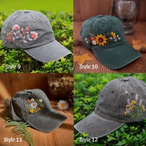 May include: Four baseball caps with floral embroidery. Styles include a gray cap with pink and white flowers, a green cap with sunflowers, a gray cap with daisies, and a gray cap with a bee and yellow flowers. Each cap has a curved brim.