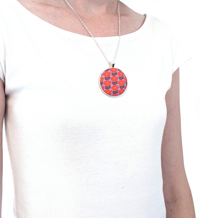 The model is wearing the fabric pendant necklace. The pendant falls to about mid-chest.