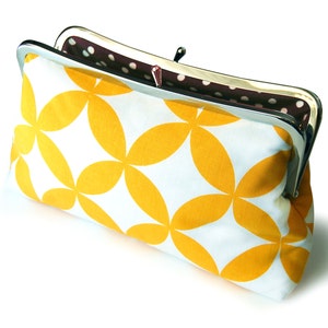 The yellow and white clutch is shown from above, slightly opened. Inside there is a brown and white polka dot print.