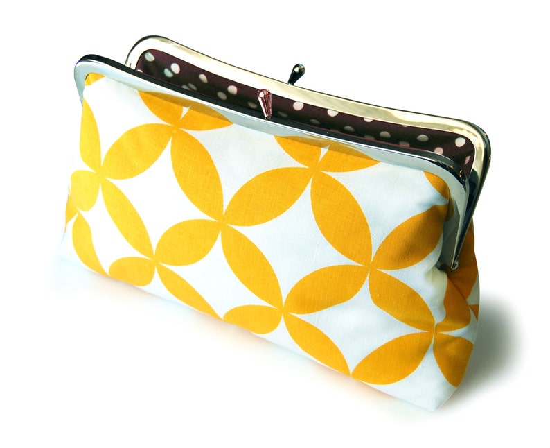 The yellow and white clutch is shown from above, slightly opened. Inside there is a brown and white polka dot print.