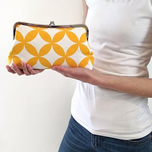 The model is holding the yellow fabric clutch off to her side.