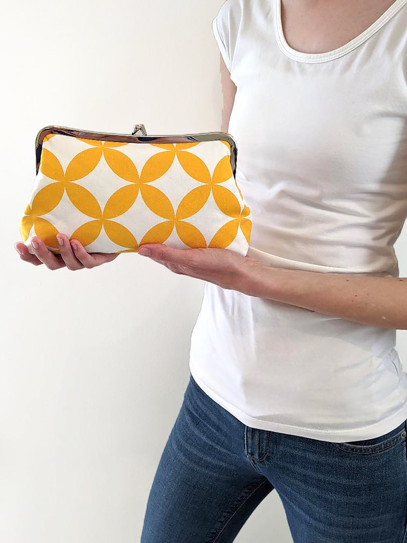 The model is holding the yellow fabric clutch off to her side.