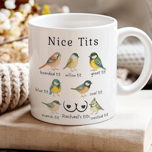 May include: White ceramic mug with the text "Nice Tits" and illustrations of various bird species, including the bearded tit and blue tit. The mug also features the text "Rachael's tits".