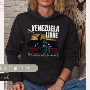 May include: Black hoodie with a white graphic print that says "Venezuela Libre hasta el final". The graphic features a yellow, blue, and red flag with a silhouette of a person standing on a pedestal.