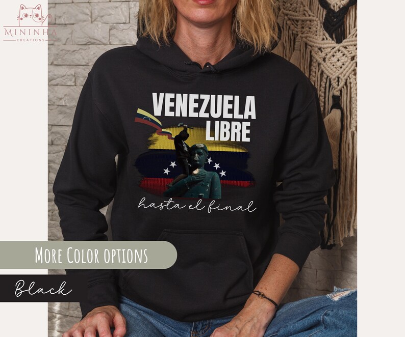 May include: Black hoodie with a white graphic print that says "Venezuela Libre hasta el final". The graphic features a yellow, blue, and red flag with a silhouette of a person standing on a pedestal.