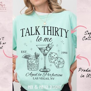 Puede incluir: Una camiseta azul claro con el texto "TALK THIRTY to me" en negro. La camiseta tambi&eacute;n presenta una copa de martini con aceitunas, dados y el texto "EST. 1994" y "Aged to Perfection LAS VEGAS, NV".