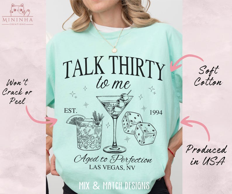 Puede incluir: Una camiseta azul claro con el texto "TALK THIRTY to me" en negro. La camiseta tambi&eacute;n presenta una copa de martini con aceitunas, dados y el texto "EST. 1994" y "Aged to Perfection LAS VEGAS, NV".