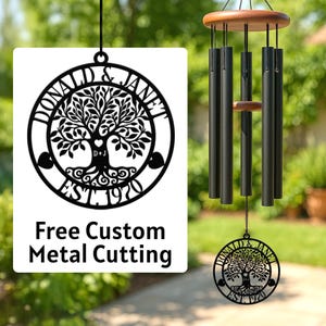 May include: Black metal wind chimes with a wooden top and a decorative metal sign. The sign features a tree design with the names "DONALD & JANET" and the year "EST. 1970". The sign also includes the text "Free Custom Metal Cutting".