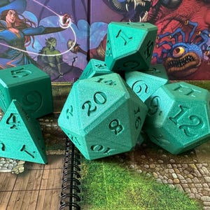 May include: A set of green dice with numbers 1 through 20. The dice are made of a textured material and have a speckled appearance.
