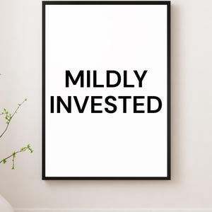 May include: A framed print with the words "MILDLY INVESTED" in bold black letters on a white background. The frame is black, and the print is displayed on a white wall.