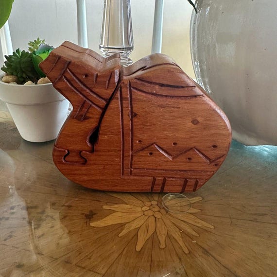 A hand-carved wooden camel that's secretly a puzzle box — you have to solve it to reveal the hidden compartment inside, no instructions included.