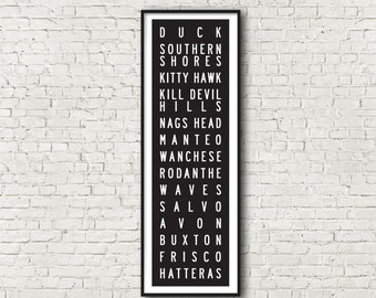 May include: Black and white print of the names of Outer Banks towns in North Carolina, including Duck, Southern Shores, Kitty Hawk, Kill Devil Hills, Nags Head, Manteo, Wanchese, Rodanthe, Waves, Salvo, Avon, Buxton, Frisco, and Hatteras.