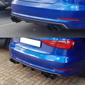 May include: The rear of a blue car with a black exhaust system. The car features black exhaust pipes and a black rear diffuser. Red taillights are visible. The car's design is sporty and modern.