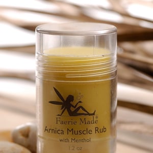May include: A clear plastic container of Faerie Made Arnica Muscle Rub with Menthol. The label features a silhouette of a fairy. The product is a yellow balm, and the container holds 1.2 oz of product.