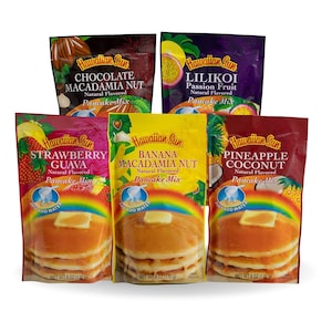 May include: Six different flavours of Hawaiian Sun pancake mix. The flavours are Chocolate Macadamia Nut, Lilikoi Passion Fruit, Strawberry Guava, Banana Macadamia Nut, Pineapple Coconut, and Pineapple Coconut. Each package has a picture of a pancake and the flavour on the front.