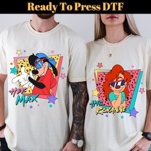May include: Two cream-colored t-shirts featuring cartoon characters Max and Roxanne from A Goofy Movie. Each shirt has a colorful 90s-style graphic with the character's name. The text "Ready To Press DTF" is at the top.