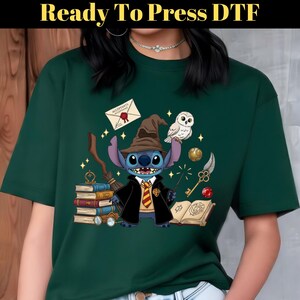 Peut inclure: Un t-shirt vert foncé avec un personnage de dessin animé Stitch habillé en sorcier, tenant une baguette magique, avec un design sur le thème de Poudlard. Le t-shirt comprend le texte "Ready To Press DTF" en haut.