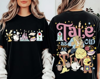 Könnte beinhalten: Ein schwarzes T-Shirt mit einem Frontmotiv aus Kandelaber, Teekanne, Schloss, Büchern und einer Rose unter einer Glaskuppel. Die Rückseite zeigt den Text Tale as old as time mit Illustrationen von Figuren, Büchern und einer Rose.