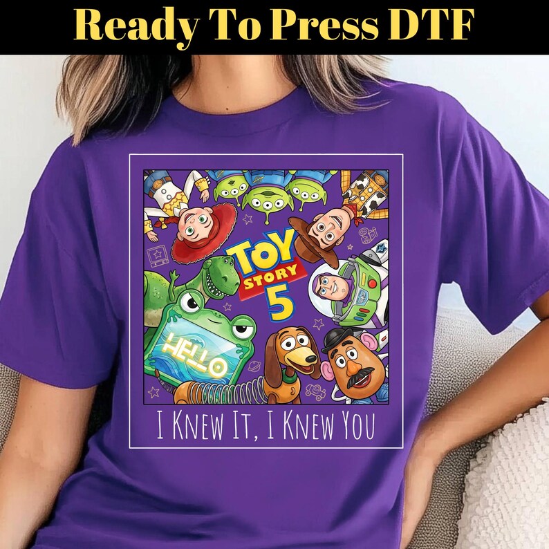 May include: A purple t-shirt featuring a graphic print of Toy Story characters including Woody, Buzz Lightyear, Jessie, Rex, Slinky Dog, Mr. Potato Head, and the Aliens. The text reads Toy Story 5 and I Knew It, I Knew You.