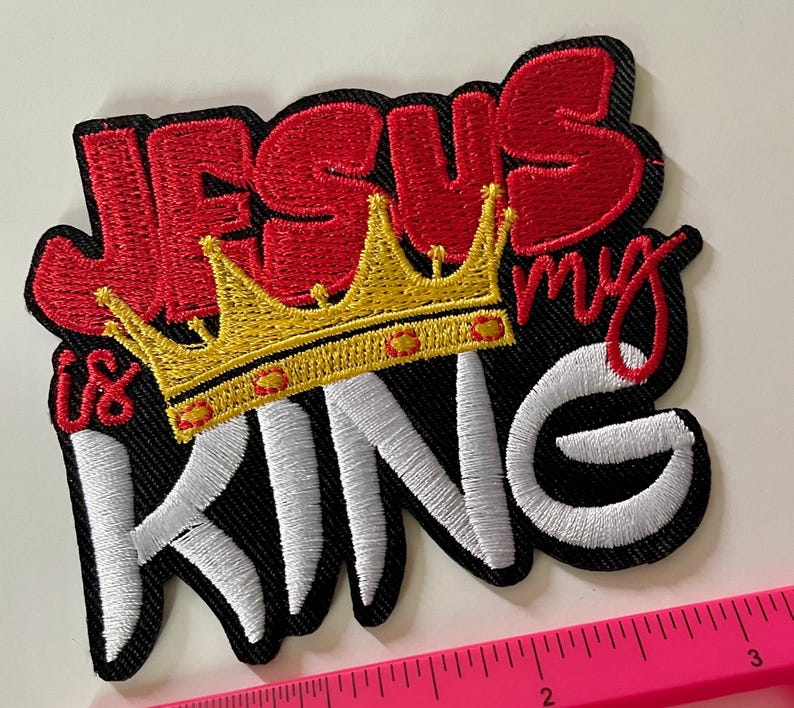 May include: Embroidered patch with the words "JESUS is my KING" in red and white thread. A gold crown with red accents sits above the word "KING". The patch has a black border.