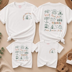 May include: Two white t-shirts with short sleeves. The front features a small tent graphic and the text "CAMPING CREW 2026". The back displays camping icons including binoculars, a backpack, a campfire, a map, trees, a mug, and a tent with the text "With love from YOSEMITE Camp Janson 2026".