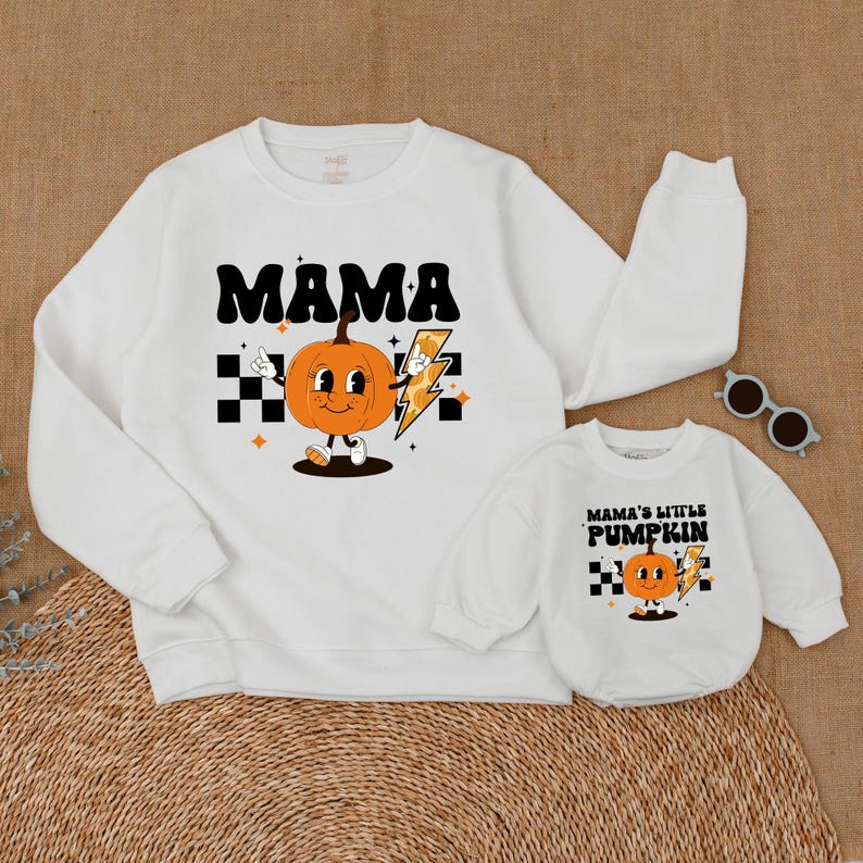 May include: White sweatshirts with a pumpkin graphic and text. The larger sweatshirt says "MAMA" and the smaller sweatshirt says "MAMA'S LITTLE PUMPKIN".