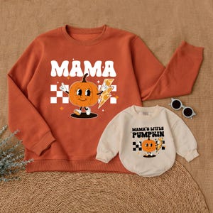 May include: A matching set of orange sweatshirts with a pumpkin graphic. The larger sweatshirt says "MAMA" and the smaller sweatshirt says "MAMA'S LITTLE PUMPKIN".