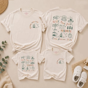 May include: Four cream-coloured t-shirts featuring camping-themed graphics. Two shirts display a small tent icon with the text "Camping Crew 2026" on the front. Two shirts feature a large back print with camping gear, trees, and "With love from YOSEMITE".