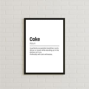 May include: A framed print with a black border against a white brick wall. The print features the word "Cake" above a definition that humorously describes eating cake at various times of the day.