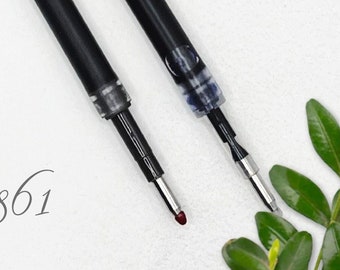 May include: Two black ink refills for a pen. One refill has a blue ink cartridge and the other has a clear ink cartridge.