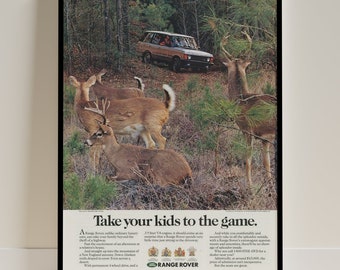 May include: A vintage advertisement for the Range Rover featuring a brown Range Rover driving through a forest with a group of deer in the foreground. The text reads "Take your kids to the game." and includes information about the vehicle's features and price.