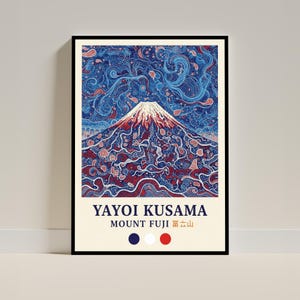 May include: A framed art print featuring a colorful illustration of Mount Fuji. The artwork, by Yayoi Kusama, showcases the mountain with a red and white peak, set against a blue background with swirling patterns. The print includes text at the bottom.