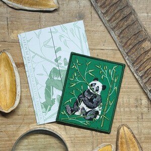 May include: A green embroidered patch with a panda bear design, eating bamboo. The patch has a stitched border. A card with a panda illustration and the text "WILDLORE GALLERY PATCHES THE PEACEFUL" is also visible, alongside the patch.
