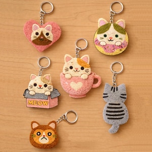 Peut inclure: Une collection de porte-clés sur le thème des chats. Les porte-clés présentent divers motifs de chats, dont un en forme de cœur, un chat dans une tasse à thé et un chat dans une boîte avec le mot "MEOW". Les porte-clés sont en matière douce et texturée.