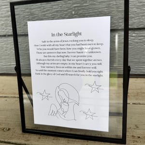 Puede incluir: Una impresión enmarcada en negro con fondo blanco y un dibujo en blanco y negro de un ángel sosteniendo un bebé. La impresión tiene el texto "In the Starlight" y un poema sobre el aprecio de los recuerdos de un ser querido que ha fallecido.